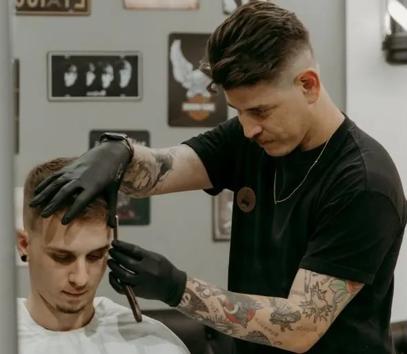 Barbeiro penteando o cabelo do cliente durante o corte