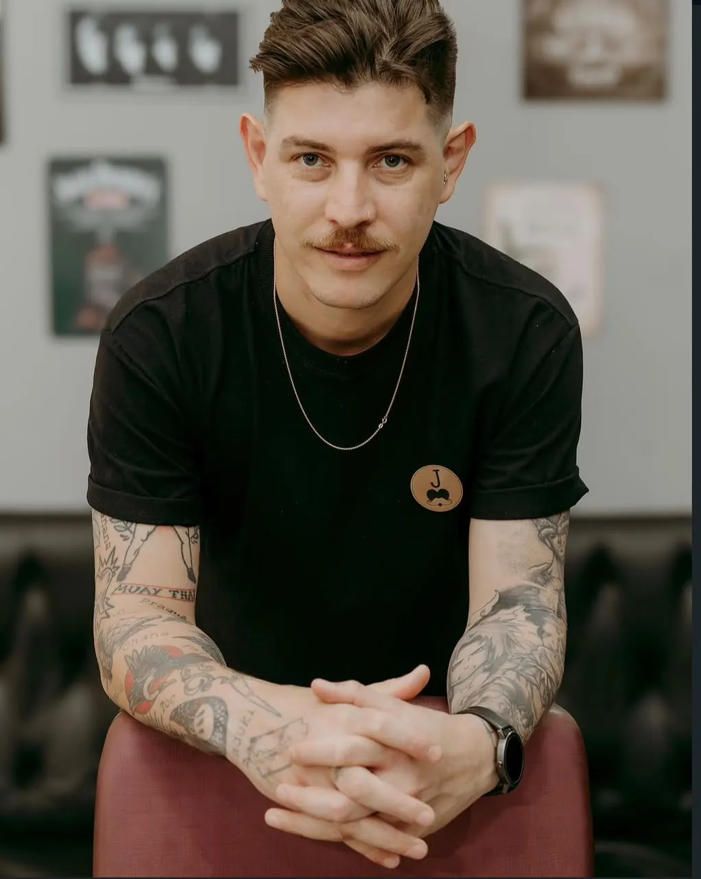 Maikon, barbeiro da Valete, de camiseta preta com o logo da barbearia