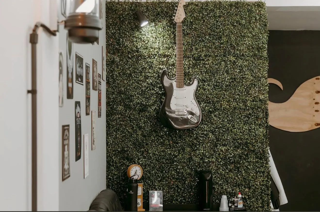 Parede verde da barbearia com uma guitarra pendurada